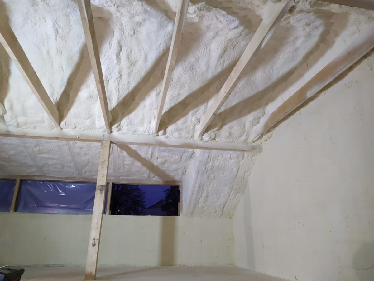 Detail stříkané izolace mezi trámy šikmé střechy