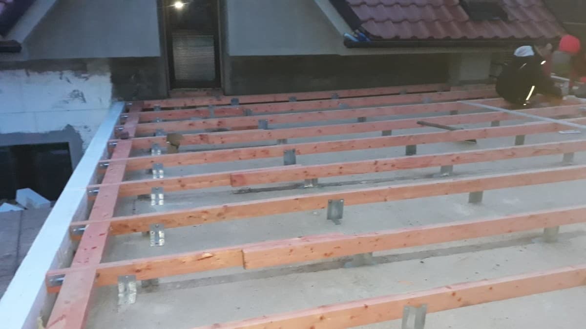 Odkrytá střešní konstrukce s dřevěnými latěmi při práci na střeše
