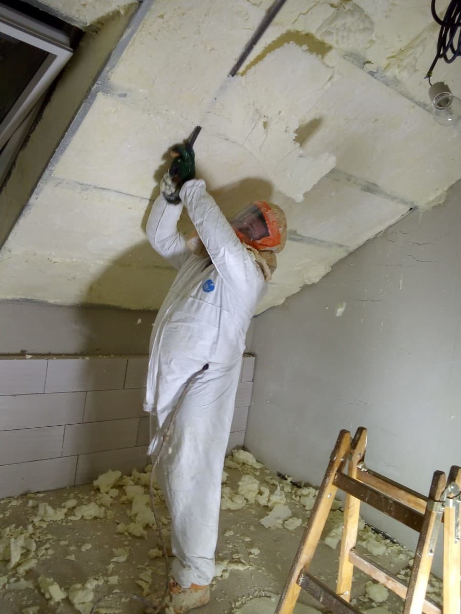 Pracovník nanáší stříkanou PUR pěnu na strop